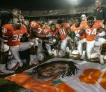 FILE - In this Nov. 23, 2006, file photo, Miami players, including Rashaun Jones (38) at left, pay their respects as they gather around a mural of teammate Bryan Pata after an NCAA college football game against Boston College in Miami. Jones was arrested Thursday, Aug. 19, 2021, in connection with the 2006 fatal shooting of his teammate Bryan Pata. Pata, a 22-year-old, 6-foot-4, 280-pound defensive lineman, was shot several times outside of his Kendall, Fla., apartment the night of Nov. 7, 2006. (Al Diaz/Miami Herald via AP)