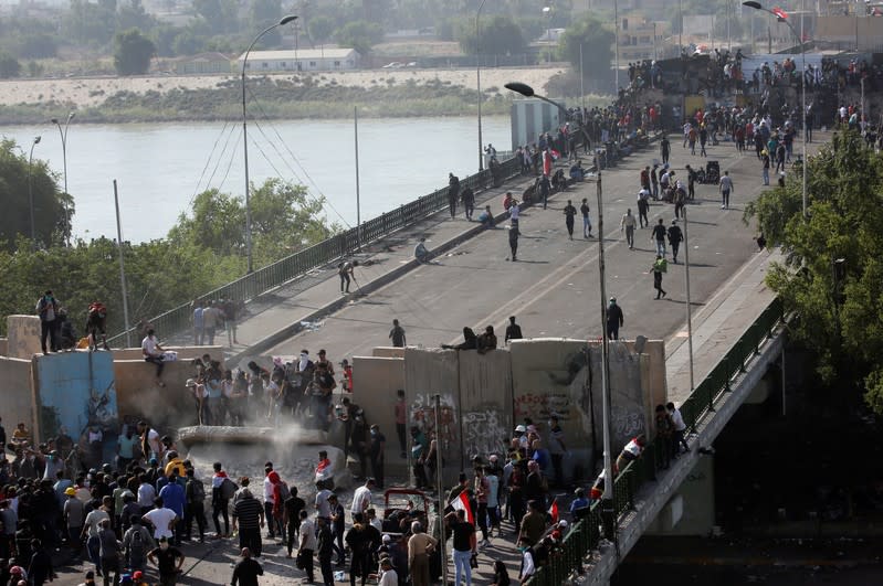 Iraqi demonstrators smash concrete walls at Sinak Bridge during the ongoing anti-government protests, in Baghdad