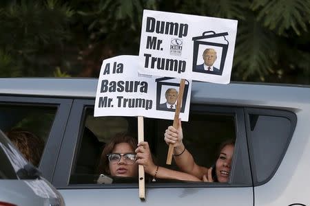 Women hold protest signs as they drive past the Luxe Hotel, where Republican presidential candidate Donald Trump was expected to speak in Brentwood, Los Angeles, California, United States July 10, 2015. REUTERS/Lucy Nicholson