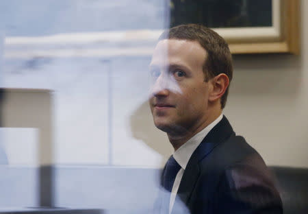 Facebook CEO Mark Zuckerberg is seen through reflective glass as he sits in the office of Senator Bill Nelson (D-FL) while he waits for a meeting in the Hart Senate Office Building in Washington, U.S., April 9, 2018. REUTERS/Leah Millis