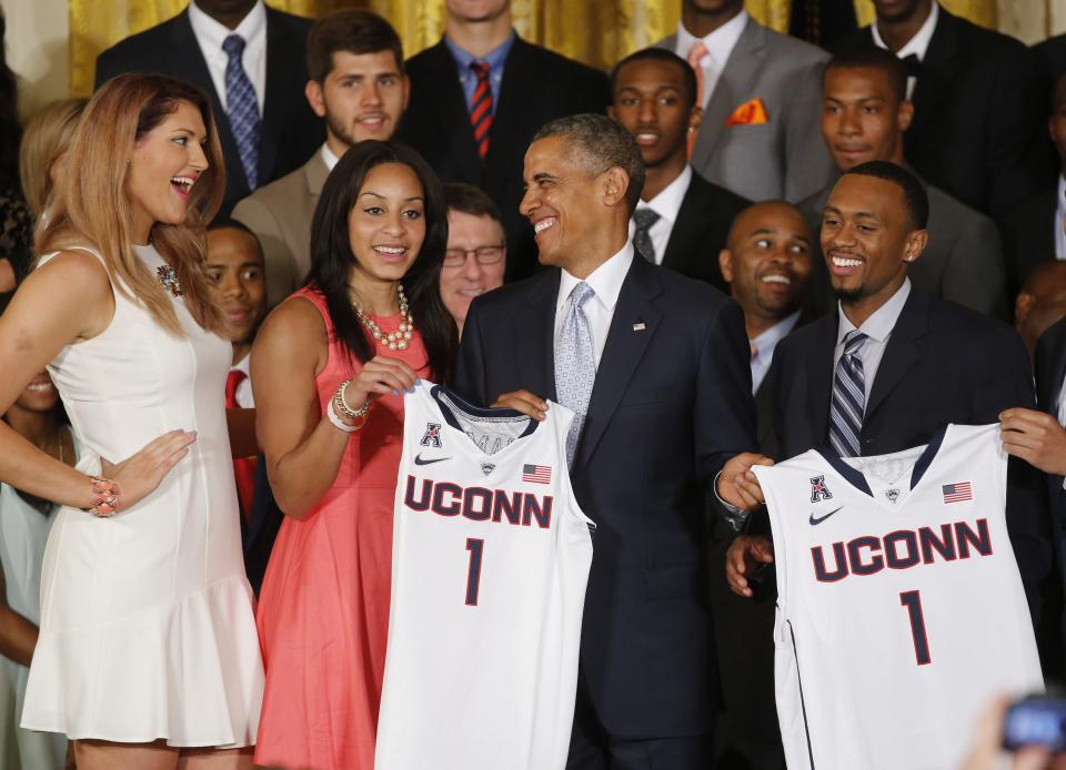 U.S. President Barack Obama laughs with UConn women's basketball stars Stefanie Dolson (L) and Bria Hartley (2nd L) as he poses with them and men's team star Ryan Boatright (R) and the jerseys of the NCAA basketball champion University of Connecticut Huskies men's and women's basketball teams in the East Room of the White House in Washington, June 9, 2014. REUTERS/Jim Bourg (UNITED STATES - Tags: POLITICS SPORT BASKETBALL)