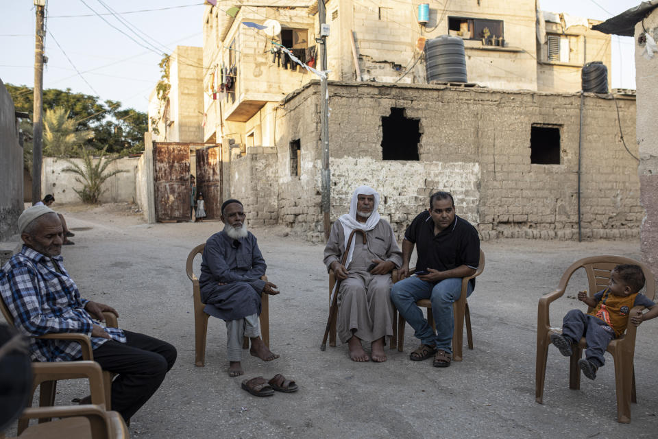 Palestinian worker Ibrahim Slaieh, center right, sits with his neighbors on a day off from work in Israel, in front of his home in Khan Younis, southern Gaza Strip, Wednesday, Aug 17, 2022. Since last year, Israel has issued over 15,000 permits allowing Palestinians from the Gaza Strip to work in Israel. Their wages are far higher than those available inside Gaza. With Gaza's economy in freefall, these permits are highly coveted and have given an important economic boost to thousands of families. But even Israel acknowledges the system is a powerful tool to preserve calm or — as critics say — control. (AP Photo/Fatima Shbair)