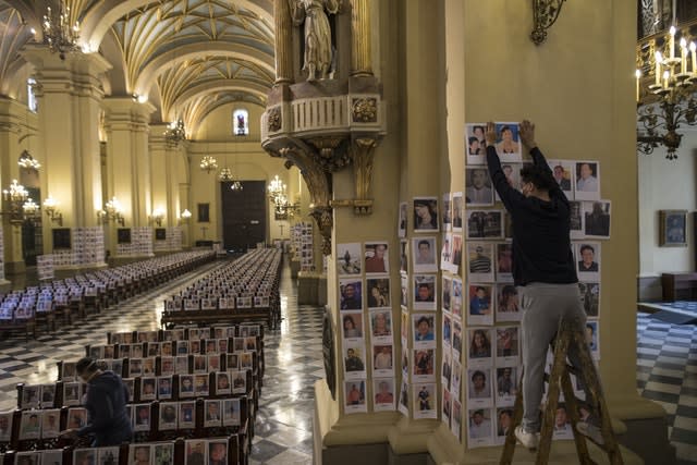 Workers stick portraits of people who died with Covid-19 inside the cathedral in Lima, Peru