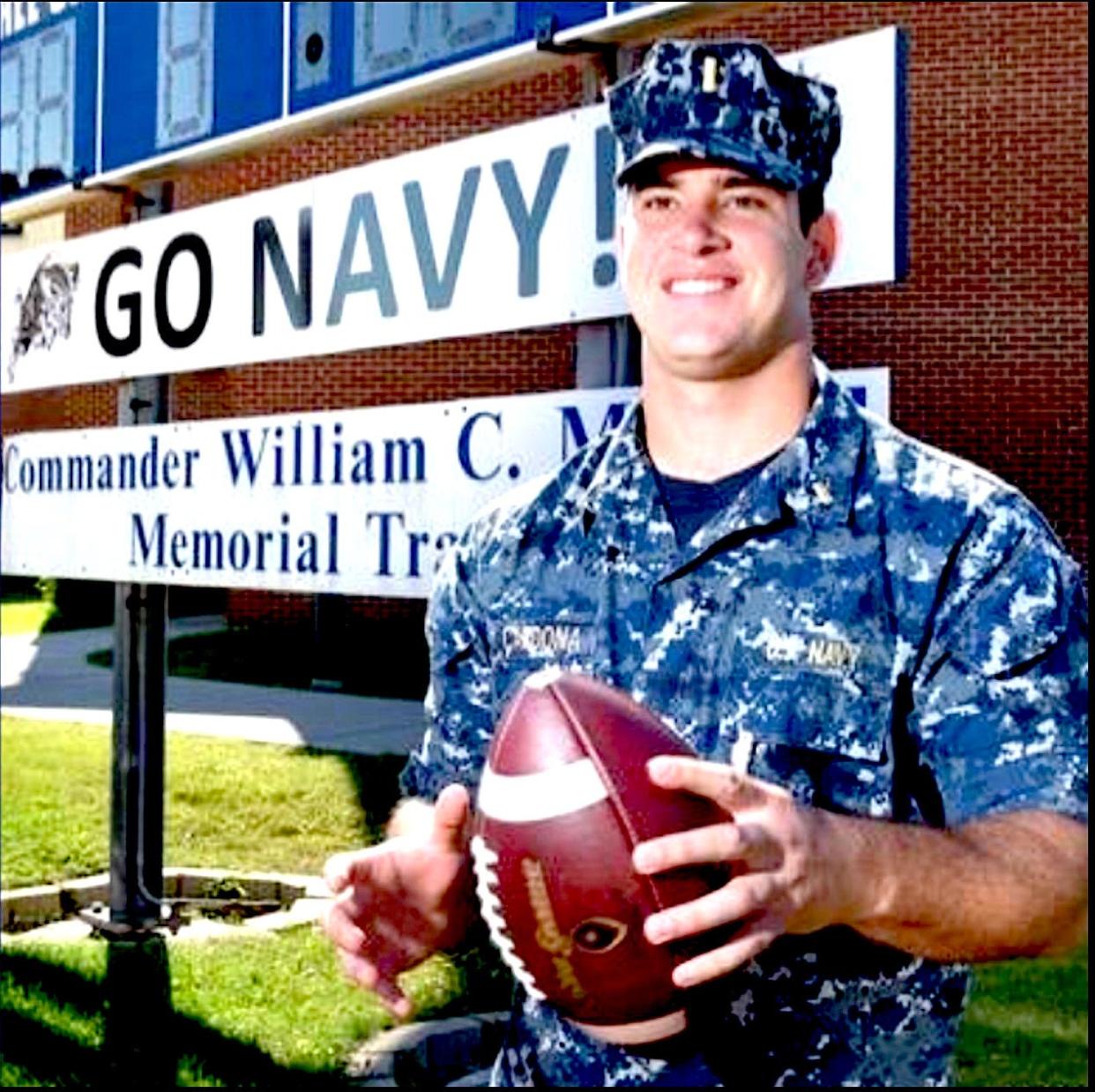 Then-Ensign Joe Cardona stands in front of the sign dedicating the track at the Naval Academy Preparatory School in Newport in 2015.