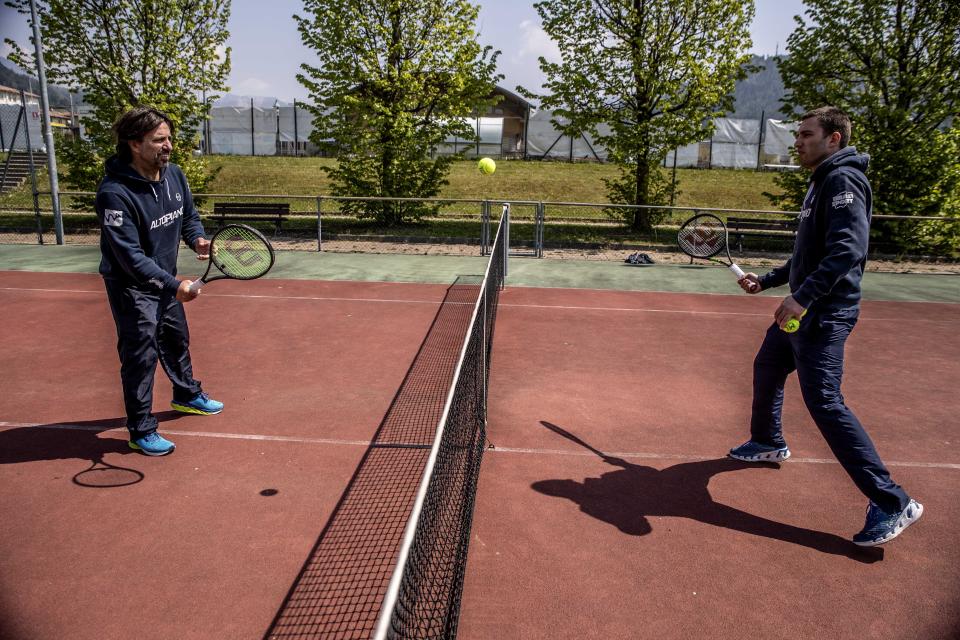 In this image take on Friday, April 24, 2020 Italian Tennis Federation coaches Luca Brasi, 55, and his brother Daniele Brasi, 41, practice on their tennis court in Rovetta, near Bergamo, northern Italy. They rely on tourism for about 50% of their yearly income, the rest comes from roughly 900 school students who follow courses throughout the winter, including some 20 under-18 professionals. (AP Photo/Luca Bruno)