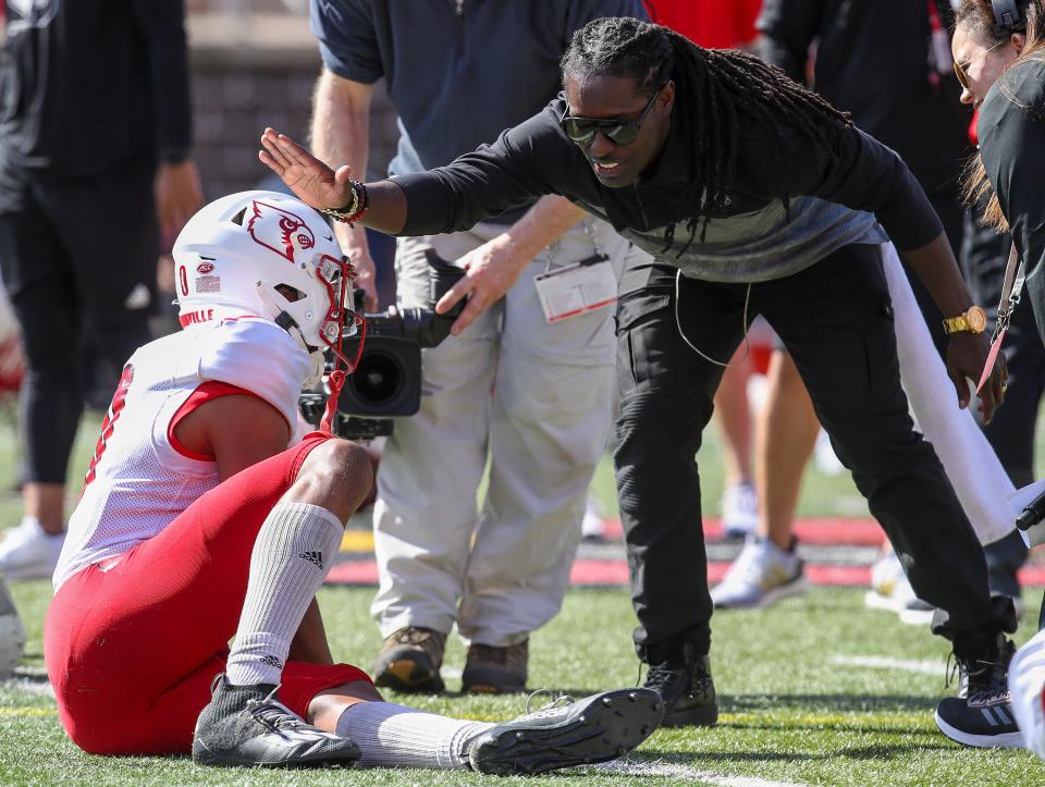 Deion Branch jokes with a player during practice at Cardinal Stadium on Sunday, April 3, 2021