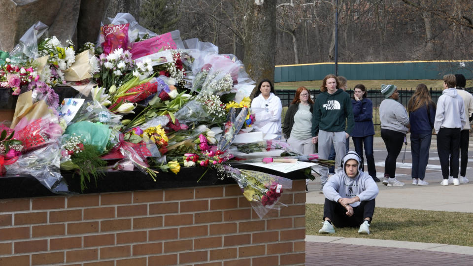 Students gather where flowers are being left at the Spartan Statue on the grounds of Michigan State University, in East Lansing, Mich., Tuesday, Feb. 14, 2023. A gunman killed several people and wounded others at Michigan State University. Police said early Tuesday that the shooter eventually killed himself. (AP Photo/Paul Sancya)
