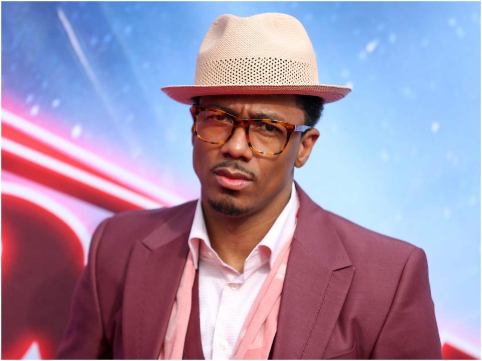 Nick Cannon wearing a tan hat and a pink suit.