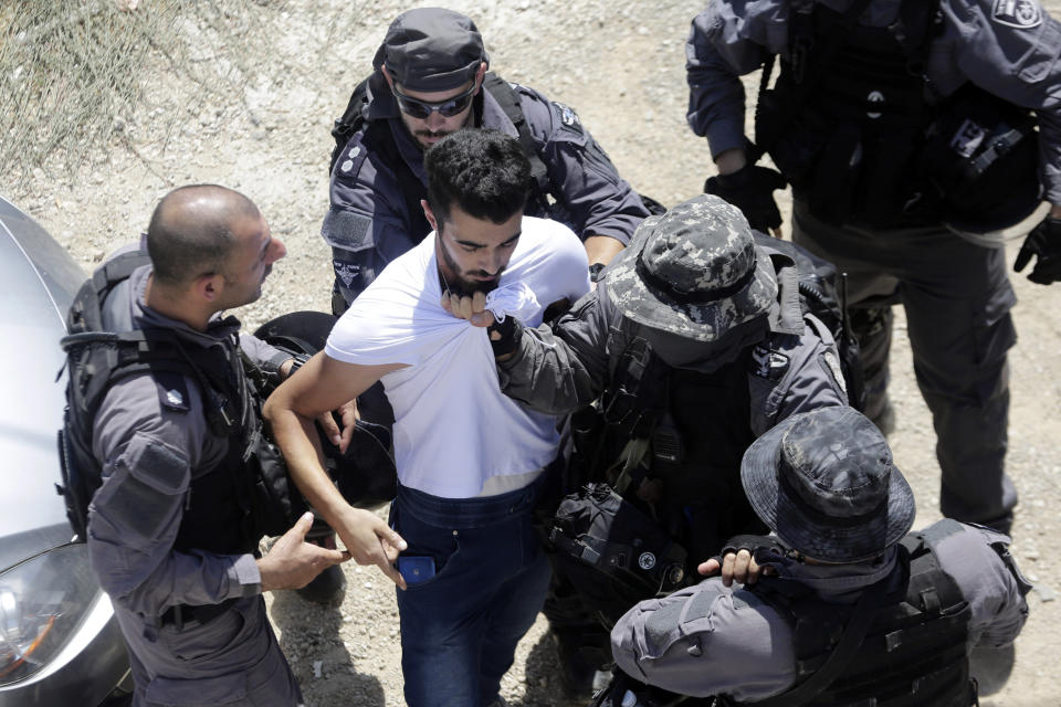 Israeli police detain a Palestinian as they demolish a house in east Jerusalem, Wednesday, Aug. 21, 2019. Jerusalem's municipality has carried out the court-ordered demolition of what it said was an illegally built Palestinian home in the city's eastern sector. Jerusalem's Palestinian population has long complained that it faces discriminatory housing policies that favor Jews. They say it is virtually impossible to get a building permit and have no choice but to build without them.(AP Photo/Mahmoud Illean)