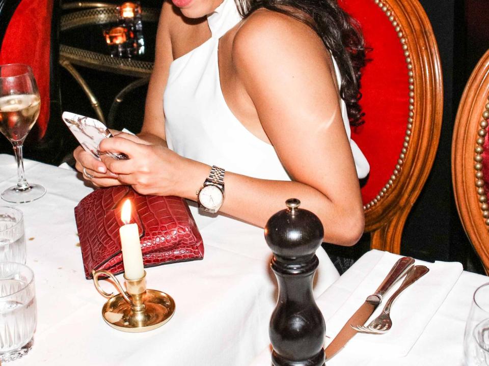 a woman sitting at a table with a cake and wine