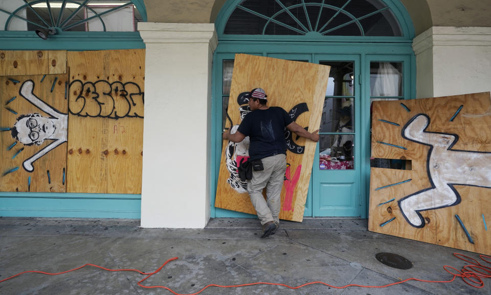 In preparation of Hurricane Ida, a workers attach protective plywood to windows and doors of a business in the French Quarter in New Orleans, Saturday, Aug. 28, 2021. (AP Photo/Eric Gay)