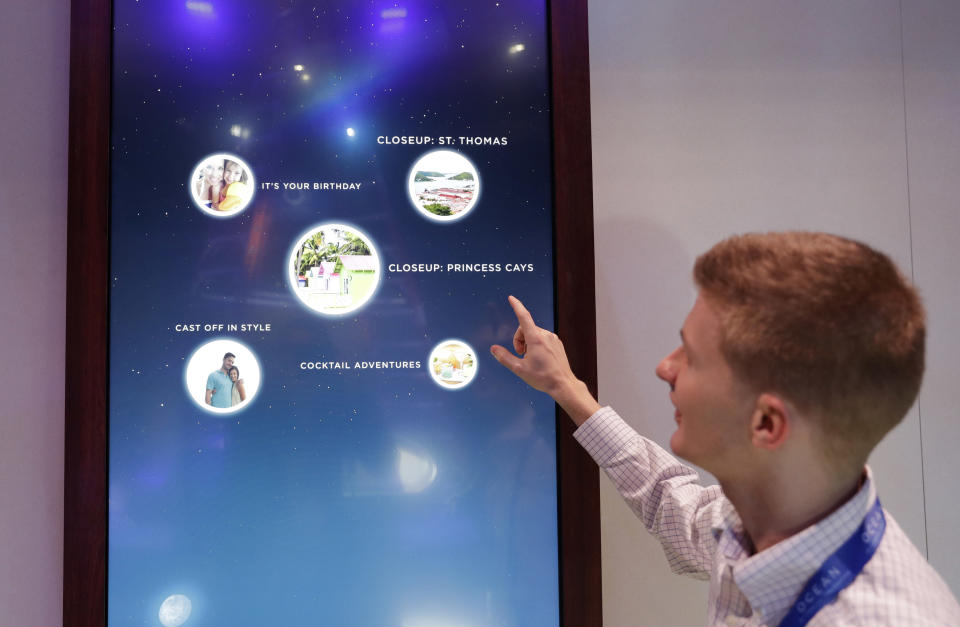 Miles Clark of Carnival Corp. demonstrates the Ocean Compass interface before CES International, Tuesday, Jan. 3, 2017, in Las Vegas. The linchpin of the concierge technology is a medallion the size of a quarter that passengers carry with them. The medallion uses wireless technologies to communicate with sensors placed around the ship and allows them to interact with displays around the ship or with crew members. (AP Photo/John Locher)