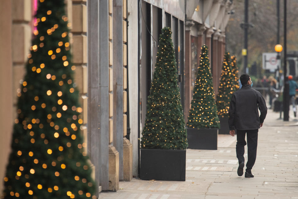 A man walks past Christmas lights outside shops in central London, as England approaches the final week of a four week national lockdown to curb the spread of coronavirus. (Photo by Dominic Lipinski/PA Images via Getty Images)