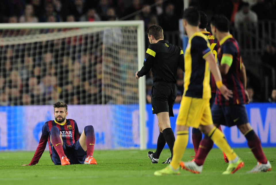 Barcelona's Gerard Pique, left sits on the pitch after getting injured during a first leg quarterfinal Champions League soccer match between Barcelona and Atletico Madrid at the Camp Nou stadium in Barcelona, Spain, Tuesday April 1, 2014. (AP Photo/Manu Fernandez)