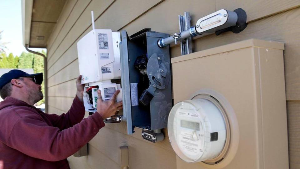 Electrician Matthew Jones, Electric Now, intalls an inverter next to a power utility meter during a solar panel installation in Nampa in November.