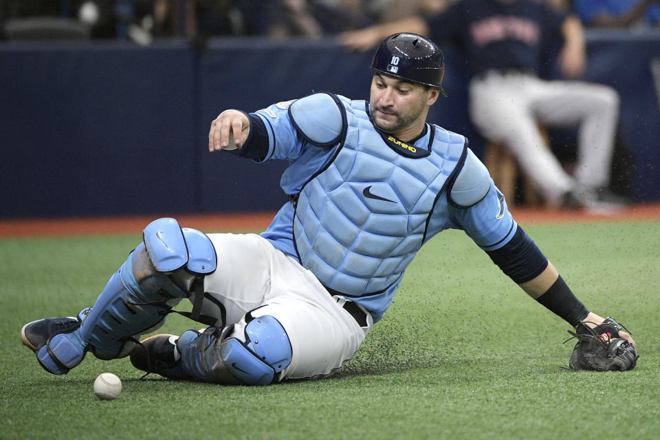FILE - In this Sept. 22, 2019, file photo, Tampa Bay Rays catcher Mike Zunino slides to pick up a wild pitch from relief pitcher Andrew Kittredge during the fourth inning of a baseball game in St. Petersburg, Fla. Making it safe for America's professional sports teams to start playing games is one thing. Making sure athletes are in game shape is another. Experts say nothing should be rushed. Athletes in the NBA, NHL and Major League Baseball all indicate that a few weeks of training is necessary before any games. (AP Photo/Phelan M. Ebenhack, File)