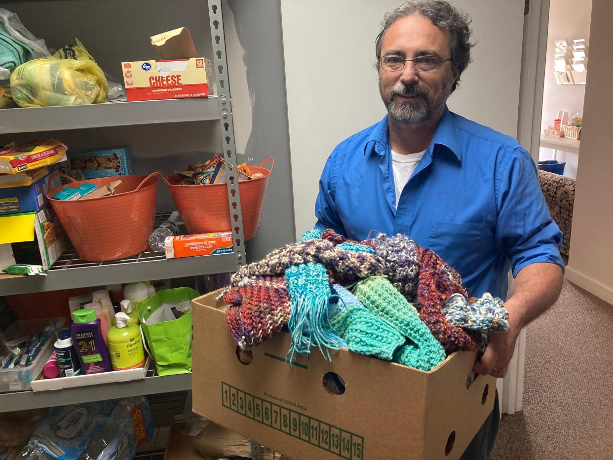 Andy O'Quinn, executive director of Trinity Outreach Center for Hope holds a box of scarves for homeless people. To his left in the TORCH supply room are other items including soap, shampoo and non-perishable food which TORCH has available for its clients.