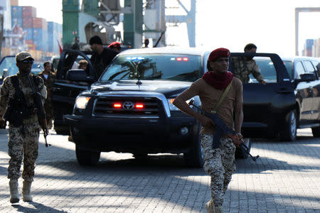 Soldiers escort government officials touring the container terminal at Aden port, Yemen December 12, 2018 . REUTERS/Fawaz Salman