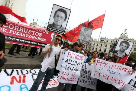 People holding pictures of victims of the guerrilla conflict in the 80s and 90s protest after Peruvian President Pedro Pablo Kuczynski pardoned former President Alberto Fujimori in Lima, Peru, December 25, 2017. REUTERS/Mariana Bazo