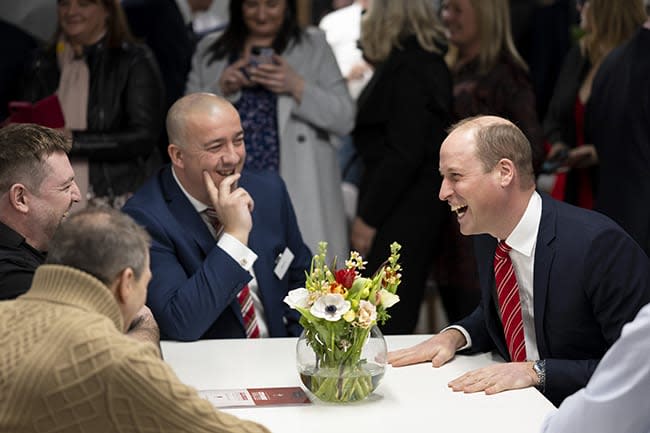 Prince William laughing with a group of people