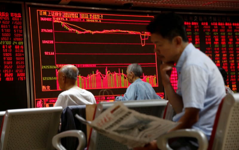 A man reads a newspaper in front of an electronic board at a brokerage house in Beijing, China, June 27, 2016. REUTERS/Kim Kyung-Hoon