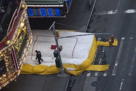 A policeman walks on an inflatable bag after it was deployed under a man threatening to jump from a roof-top building in Times Square, New York October 16, 2014. REUTERS/Adrees Latif