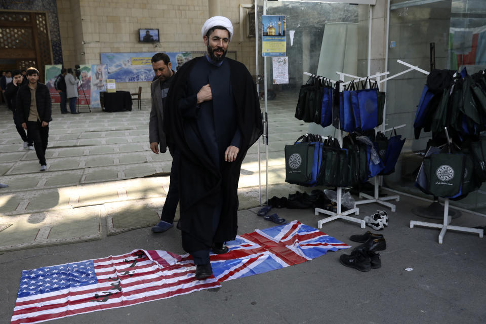 A cleric walks on the U.S. and British flags while leaving a gathering to commemorate the late Iranian Gen. Qassem Soleimani, who was killed in Iraq in a U.S. drone attack on Jan. 3, and victims of the Ukrainian plane that was mistakenly downed by the Revolutionary Guard last Wednesday, at the Tehran University campus in Tehran, Iran, Tuesday, Jan. 14, 2020. M (AP Photo/Vahid Salemi)