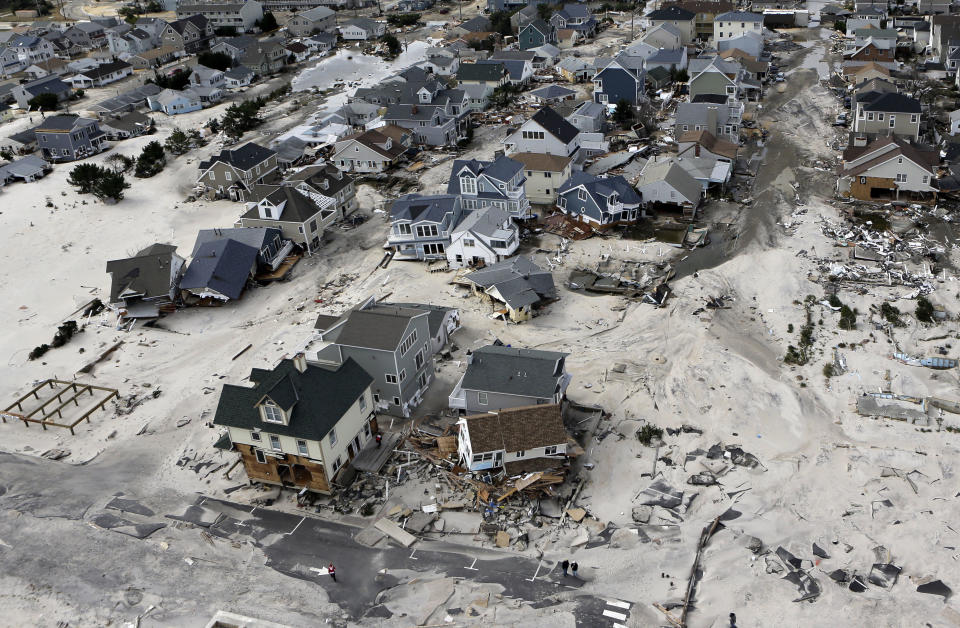 FILE - In an Oct. 31, 2012, file aerial photo, the destroyed and damaged homes are left in the wake of Superstorm Sandy in Seaside Heights, N.J. The economic and financial impact of global warming is complex and not well understood. In some scenarios there would be economic benefits for countries that get warmer and wetter and consequently more fertile agriculturally. Drier weather in some regions would result in sharply lower crop yields. Overall, changes in climate are expected to cause significant disruptions that also exact an economic toll. Advisers to the Intergovernmental Panel on Climate Change say that the world economy may suffer losses of between 0.2 percent and 2 percent of income if temperatures rise by 2 degrees from recent levels. (AP Photo/Mike Groll, File)