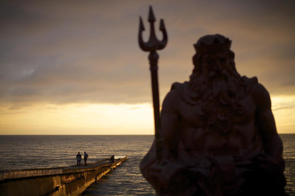 In this photo taken on Thursday, Nov. 28, 2013, the statue of ancient Roman god Neptune sits in guard of the beach during the sunset at an embankment of Sochi, Russia. As the Winter Games are getting closer, many Sochi residents are complaining that their living conditions only got worse and that authorities are deaf to their grievances. (AP Photo/Alexander Zemlianichenko)