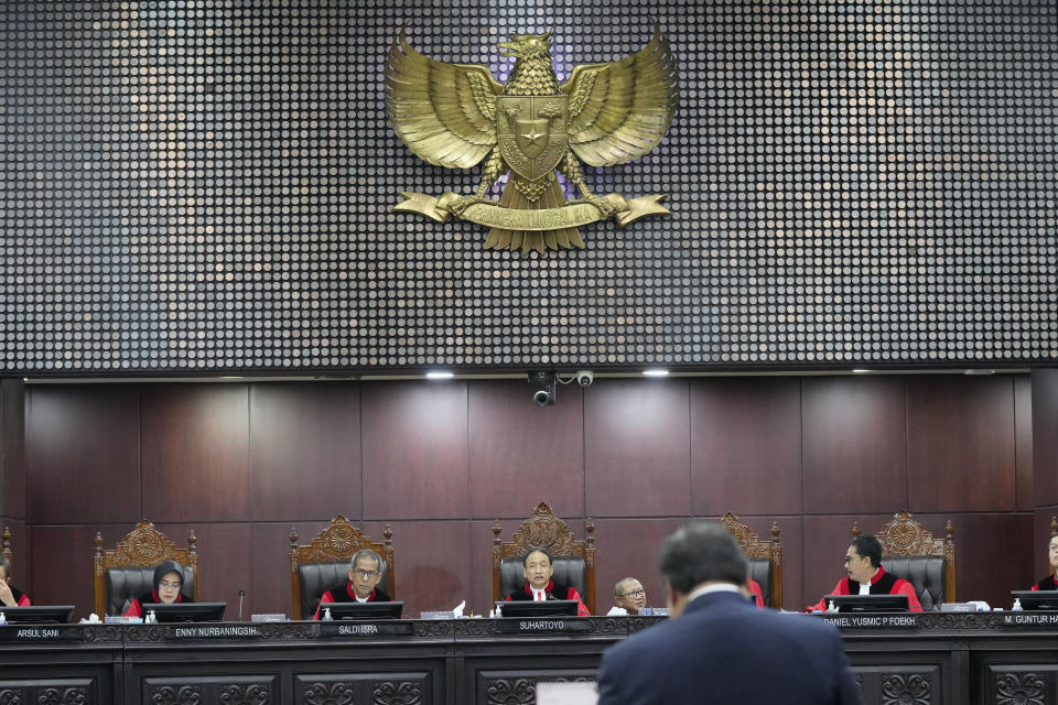Chief Judge Suhartoyo, center, listens as Coordinating Minister for Economics Airlanga Hartarto delivers his statement during a hearing on the presidential election result dispute at the Constitutional Court in Jakarta, Indonesia, Friday, April 5, 2024. (AP Photo/Dita Alangkara)