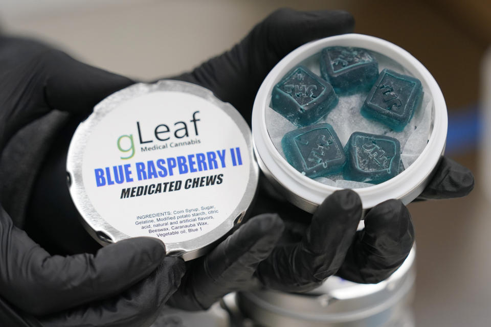 A worker displays a tin of Green Leaf medicated chews are stacked up at the company's plant in Richmond, Va., Thursday, June 17, 2021. The date for legalizing marijuana possession is drawing near in Virginia, and advocacy groups have been flooded with calls from people trying to understand exactly what becomes legal in July. (AP Photo/Steve Helber)