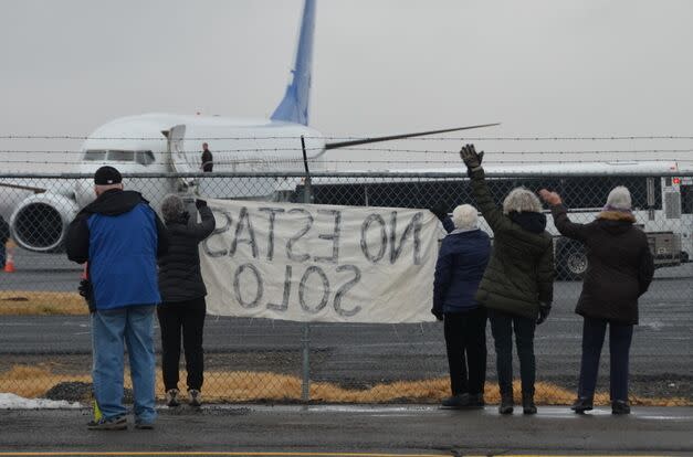 Activists in Yakima, Wash., wave encouragement to a detainee in shackles boarding a U.S. Immigration and Customs Enforcement flight bound for Mesa, Arizona. ICE moved the flights to the central Washington city in May after King County officials booted them from Boeing Field near Seattle, saying deportations raised troubling human rights concerns.