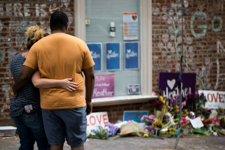 A couple comforts each other as they observe the flowers and hand-written messages at a makeshift memorial dedicated to Heather Heyer off the mall in downtown Charlottesville