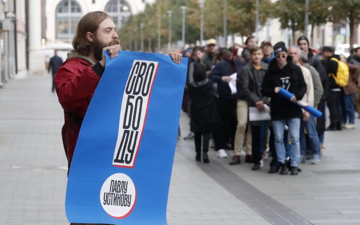 A man holds a sign reading 'Freedom for Pavel Ustinov' as others wait their turn in the single-person picket outside the presidential administration - REX