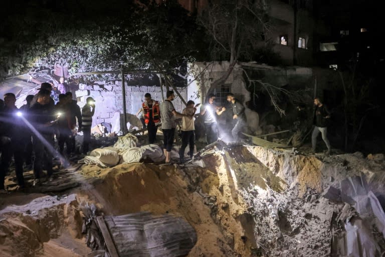 People search with flashlights by an impact crater at the site of a building that was hit by Israeli bombardment in Rafah in the southern Gaza Strip (-)