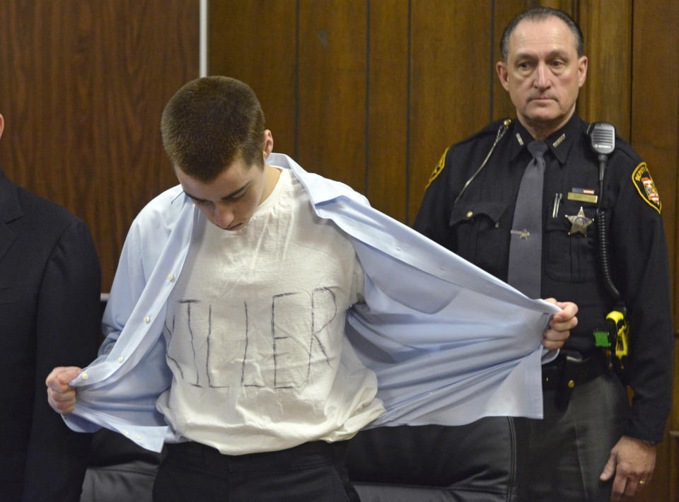 T.J. Lane unbuttons his shirt during sentencing Tuesday, March 19, 2013, in Chardon, Ohio. Lane, was given three lifetime prison sentences without the possibility of parole Tuesday for opening fire last year in a high school cafeteria in a rampage that left three students dead and three others wounded. Lane, 18, had pleaded guilty last month to shooting at students in February 2012 at Chardon High School, east of Cleveland. Investigators have said he admitted to the shooting but said he didn't know why he did it. Before the case went to adult court last year, a juvenile court judge ruled that Lane was mentally competent to stand trial despite evidence he suffers from hallucinations, psychosis and fantasies. (AP Photo/The News-Herald, Duncan Scott, Pool)