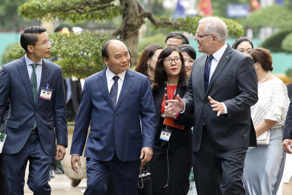 Australian Prime Minister Scott Morrison, right, talks with his Vietnamese counterpart Nguyen Xuan Phuc, center, while walking at the Presidential Palace in Hanoi, Vietnam, Friday, Aug. 23, 2019. Morrison is on a three-day official visit to Vietnam. (AP Photo/Duc Thanh)