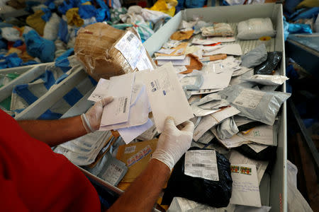 A Palestinian worker displays items sent by mail eight years ago as they reach destination, after Israel allowed the letters and goods into the West Bank from Jordan, where they were being held, Jericho, in the occupied West Bank August 19, 2018. REUTERS/Mohamad Torokman