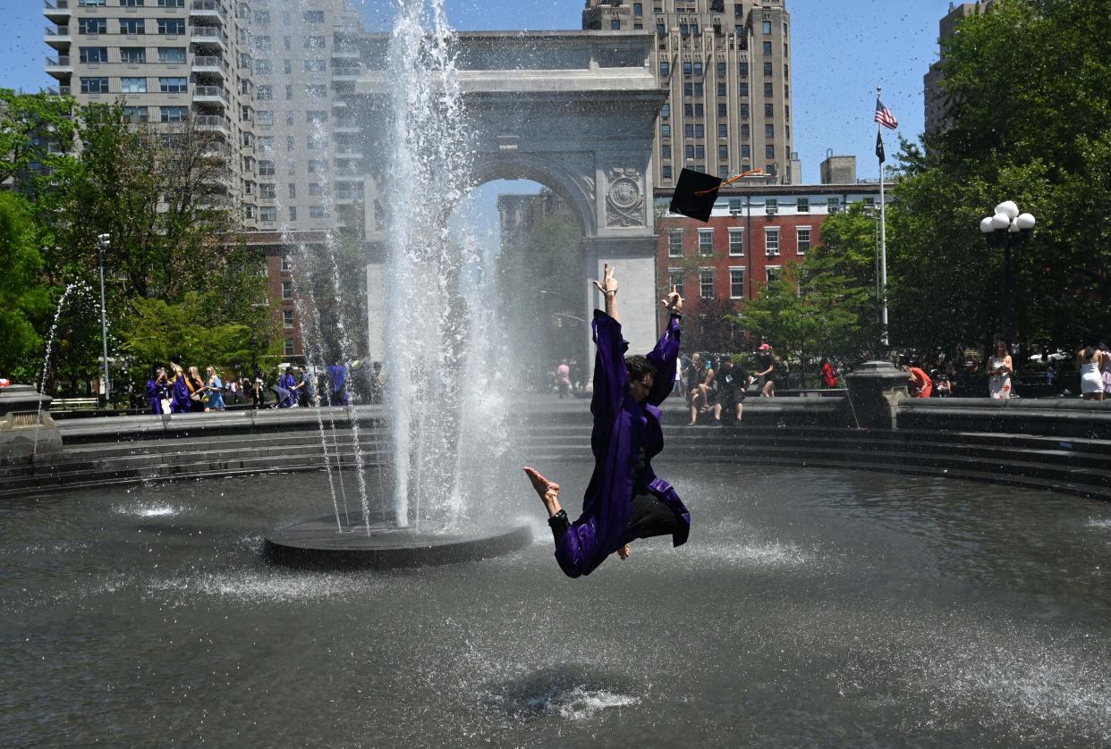 A graduate jumps in the air in the fountain at Washington Square Park on May 19, 2021 in New York. (Photo by TIMOTHY A. CLARY / AFP)