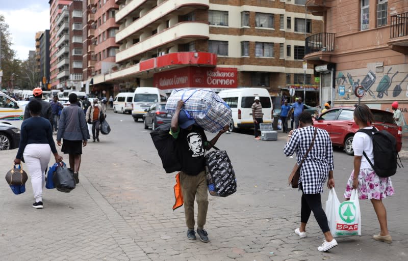 A man carries luggage as he walks to a taxi rank as residents of a number of African cities where the coronavirus is spreading are heading to the countryside to try to escape from the disease, in Johannesburg