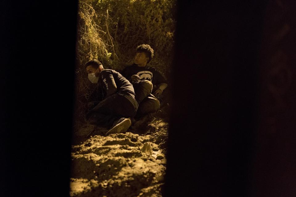 Salvadoran migrant Cesar Jobet, right, and Daniel Jeremias Cruz hide from U.S. border agents after they dug a hole in the sand under the border wall and crossed over to the U.S. side, in Playas de Tijuana, Mexico, Friday, Nov. 30, 2018. When the two youths were detected by agents they ran back to the Mexican side. (AP Photo/Ramon Espinosa)