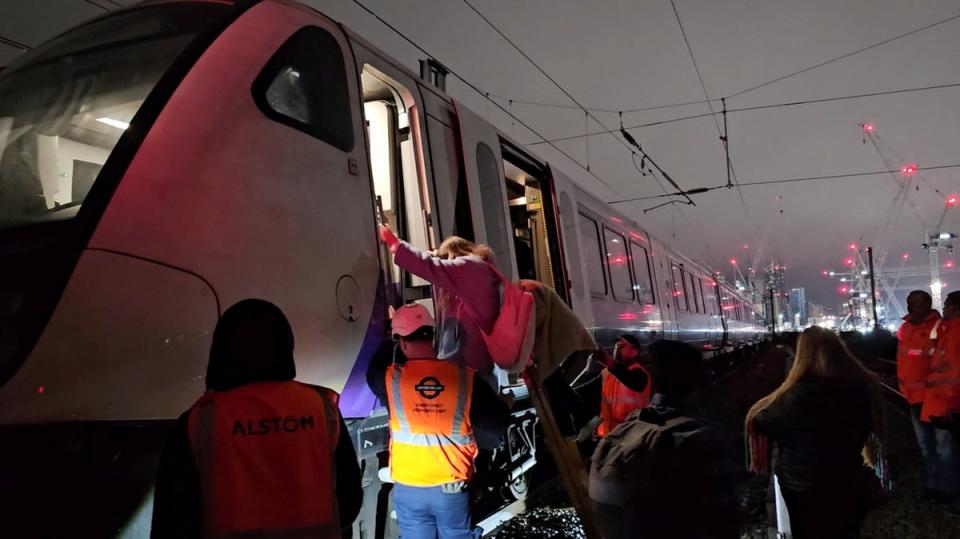 Officials assist passengers to get down from a train stuck on the Elizabeth Line after damaged overhead cables blocked railway lines in London (via REUTERS)