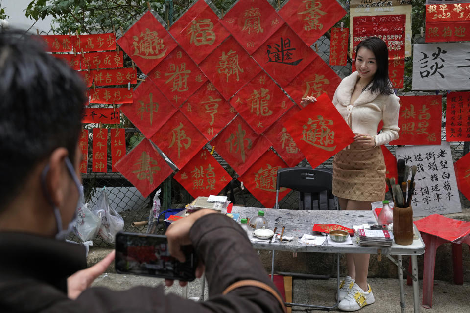 Hayley Au poses for a photograph after writing a "Fai Chun" with Chinese characters reading "Good Fortune" traditional decorations with Chinese calligraphy, which sell for HK$ 250 each (US $ 32), in Hong Kong on Jan. 26, 2022. In the runup to the Lunar New Year, calligraphers set up on the streets of Hong Kong to write ink-brush phrases on traditional red paper banners for homes and offices. (AP Photo/Kin Cheung)