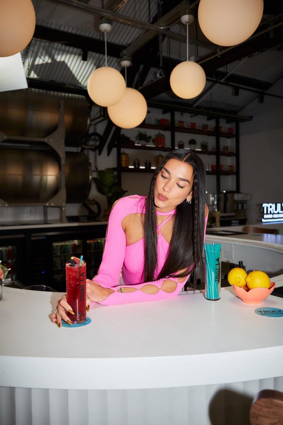 The new Los Angeles taproom will offer "Trulixers," a selection of mixed drinks using Truly Hard Seltzer as a base and featuring a variety of locally sourced, fresh ingredients as well as vibrant garnishes. Dua Lipa can be seen sampling Truly LA's "Berry Bramble."