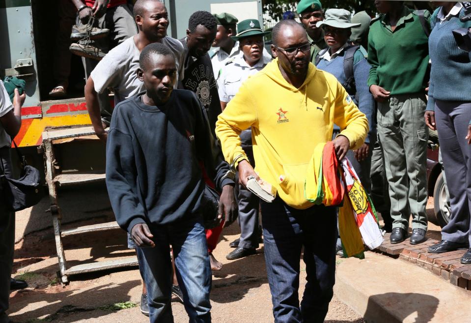 Pastor and activist Evan Mawarire, right, arrives handcuffed at a magistrates' court in Harare on Friday (Tsvangirayi Mukwazhi/AP)