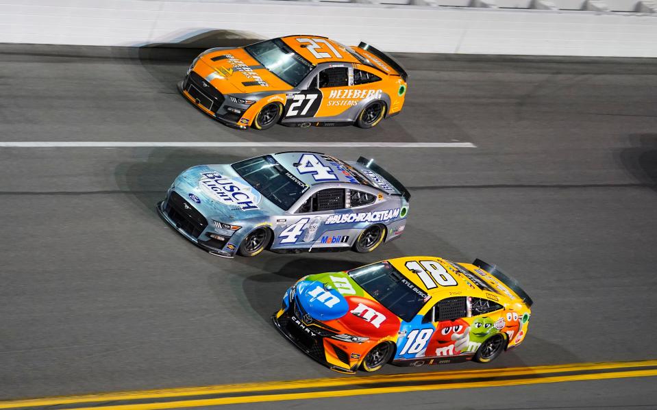 Feb 17, 2022; Daytona, FL, USA; NASCAR Cup Series driver Kyle Busch (18), driver Kevin Harvick (4) and driver Jacques Villeneuve (27) race three wide during the Bluegreen Vacations Duel 2 at Daytona International Speedway. Mandatory Credit: Mike Dinovo-USA TODAY Sports