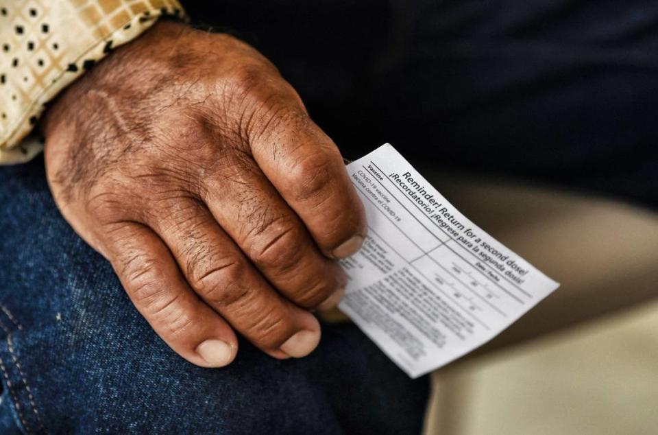 A man holds his COVID vaccination card while waiting to get his shot at at an event by the Episcopal Farmworker Ministry targeting members of the Hispanic community in August 2021.