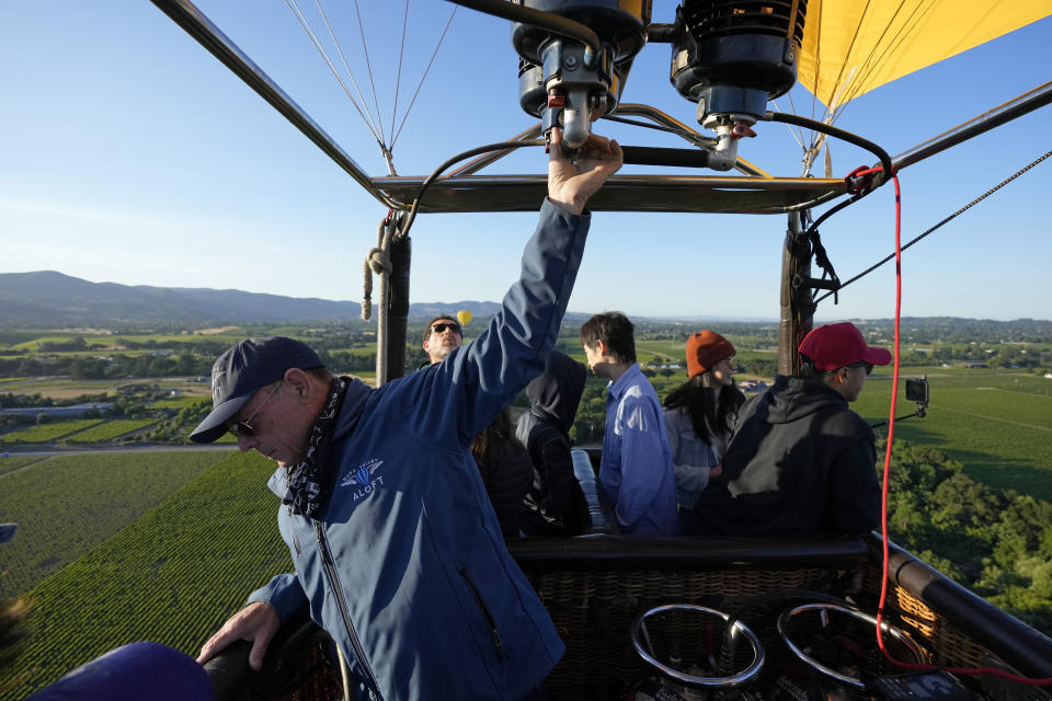 Pilot Jimmy Marshall prepares to land a Napa Valley Aloft hot air balloon in Napa, Calif., Monday, June 19, 2023. This year, wine grapes are thriving after a winter of record amounts of rain fell in California, but a recent trip high above the valley in a hot air balloon revealed miles of lush, green vineyards — the only blemish coming from shadows cast by the balloons themselves. (AP Photo/Eric Risberg)
