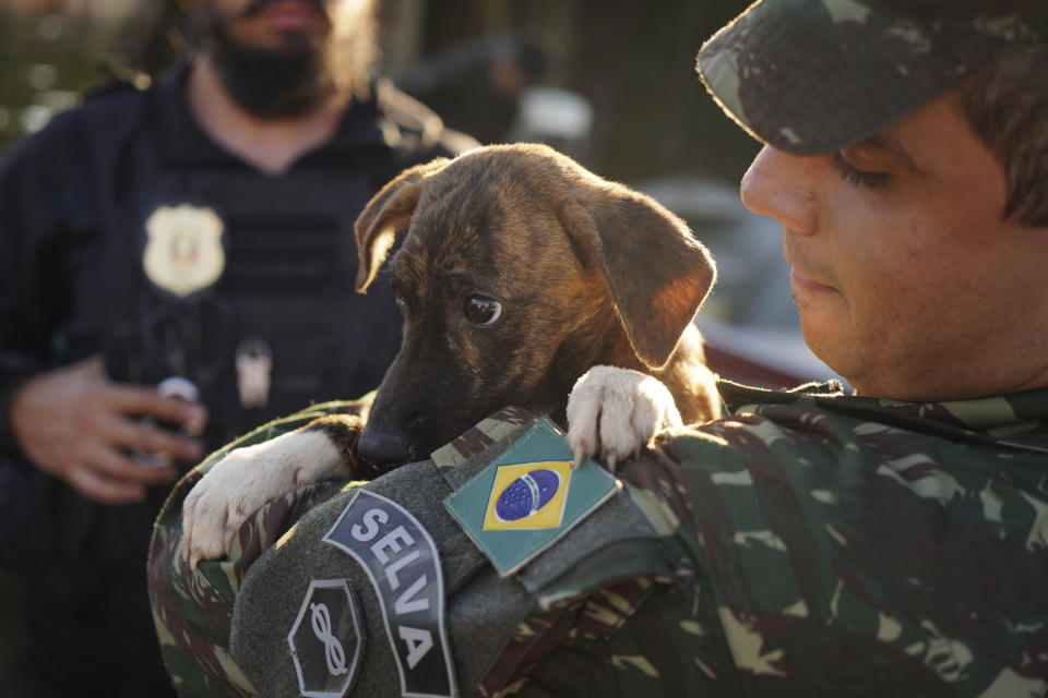 FILE - A Brazilian soldier carries a dog after rescuing it from a flooded area after heavy rain in Canoas, Rio Grande do Sul state, Brazil, Thursday, May 9, 2024. A top United Nations official says even though climate change makes disasters such as cyclones, floods and droughts more intense, more frequent and striking more places, fewer people are dying from those catastrophes globally. Thats because of better warning, planning and resilience. (AP Photo/Carlos Macedo, File)