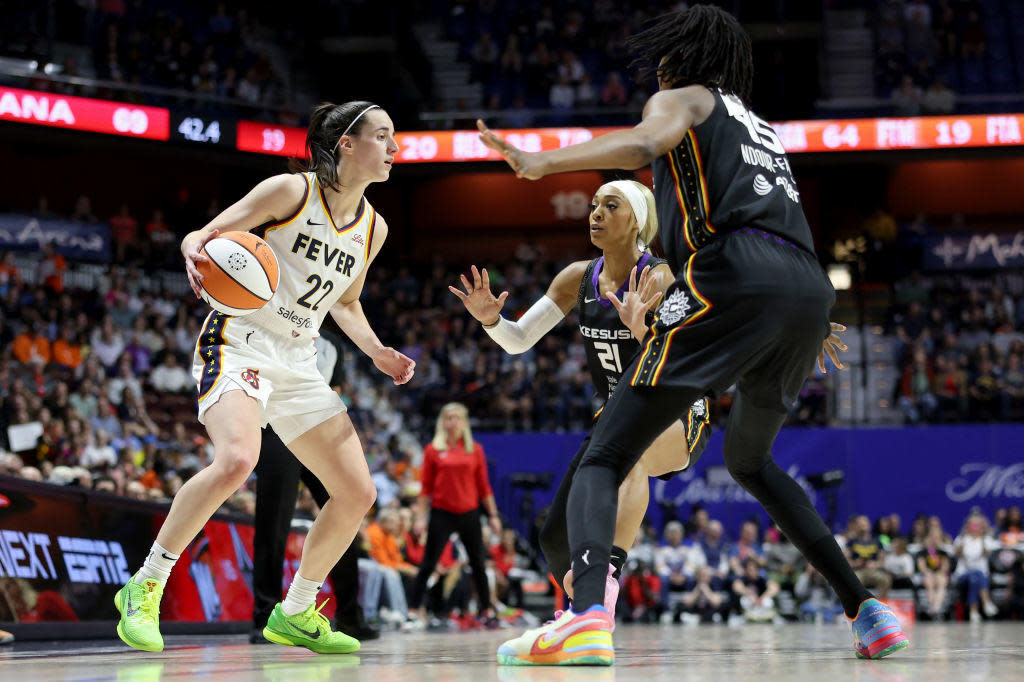 Caitlin Clark of the Indiana Fever dribbles the ball against Astou Ndour-Fall and DiJonai Carrington of the Connecticut Sun in a WNBA game at Mohegan Sun Arena on May 14, 2024, in Uncasville, Connecticut. / Credit: Getty Images